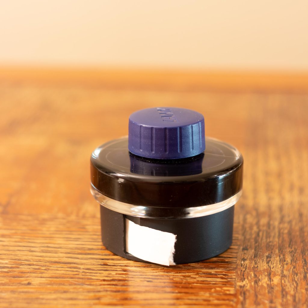 Gros plan sur le flacon de l'encre Lamy Bleu Noire montrant le rouleau de papier buvard à l'intérieur du pourtour en plastique.